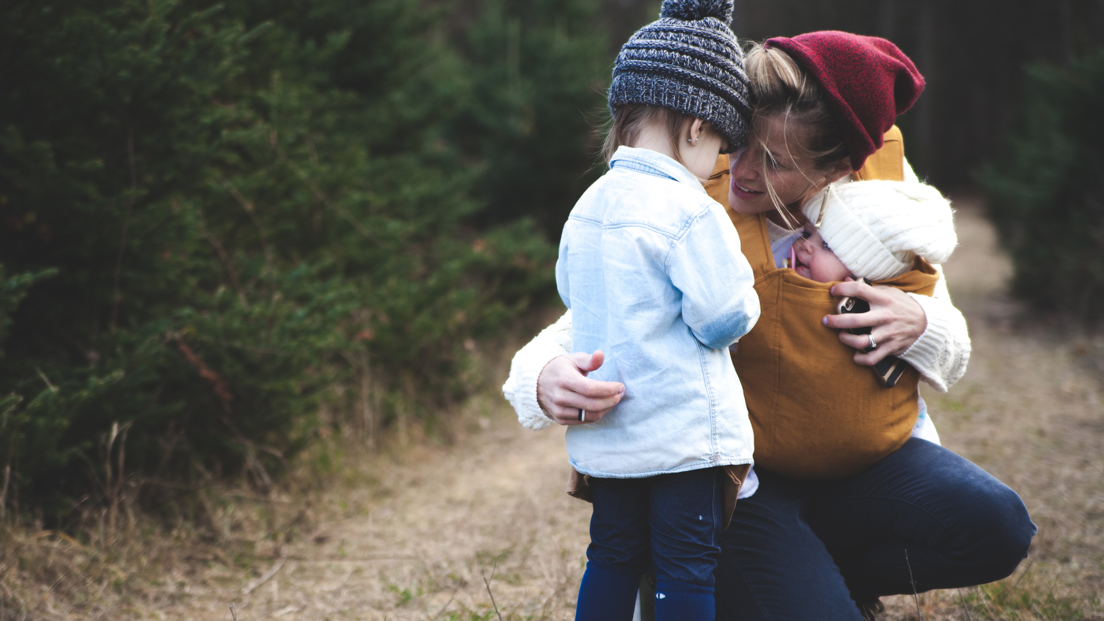 Mom with baby, hugging preschool child, anxious attachment and motherhood
